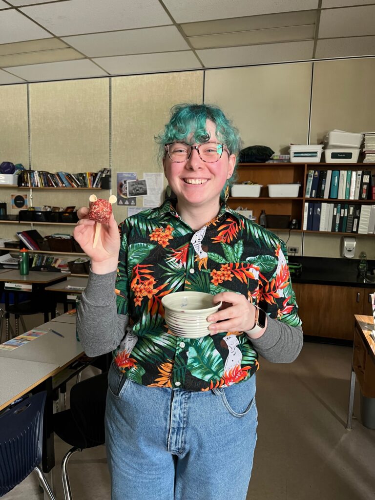 A picture of Molly in a classroom holding a small plush mouse.