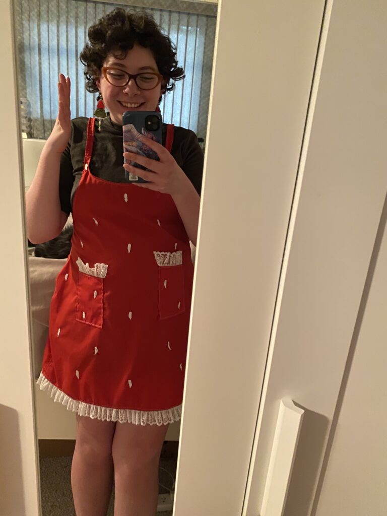 A mirror selfie of Molly with shorter hair showing off a finished strawberry-themed dress.